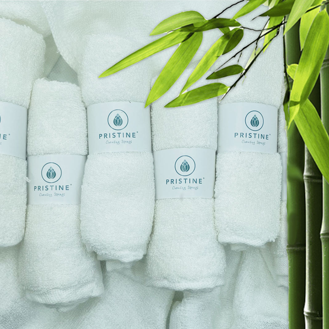 Bamboo Towels rolled up with Pristine logoed sleeve next to bamboo shoot.