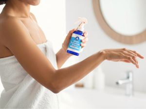 woman spraying Pristine Body Cleansing Spray onto her arm