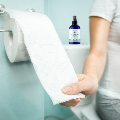 Pristine toilet paper spray on back of toilet. woman pulls toilet paper from roll to spray.