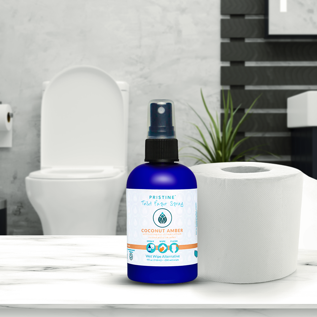 Pristine Toilet Paper Spray 4 oz bottle placed on countertop next to toilet paper.